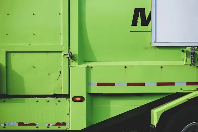 Junk removal service — closeup image of the side of a bright green dumpster truck